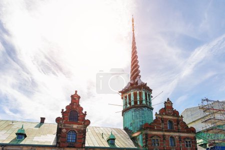 Dragones retorcidos Spire Old stock exchange building roof, Borsen, Copenhague Dinamarca contra la luz del cielo azul del sol. Arquitectura histórica.