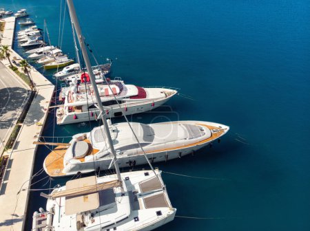 Scenic aerial  view many yachts boats moored at Croatian bay harbor shore blue turquoise clear water at bright summer sunny day. Top above Mediterranean sea marina. Boat vessel charter service.