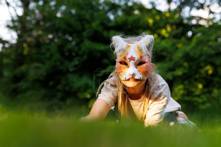 Linda niña pequeña niña usar gato máscara peluda disfrutar de divertirse jugando al aire libre en el parque de la calle del bosque. Niños therian animal salvaje carácter moda cultura fan. Manifestación social adolescente hobby.