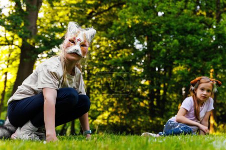 Cute young little kid girl wear cat furry mask enjoy have fun playing outdoors in forest street park. Children therian wild animal character trendy fan culture. Teenager social expression hobby.