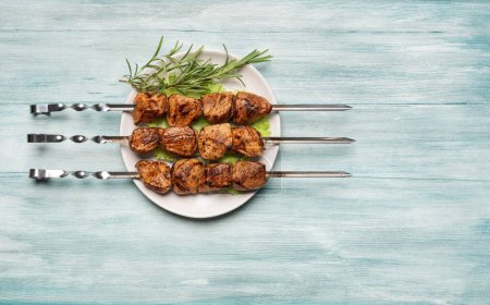 Foto de Kebab de shish apetitoso en un plato con lechuga y romero sobre un fondo de madera azul. Vista superior. - Imagen libre de derechos