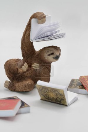 Foto de Una toma vertical de un juguete en miniatura perezoso con libros - Imagen libre de derechos