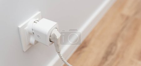 Foto de Uso de enchufe inteligente Wi-Fi en la pared en un hogar inteligente, controlando el consumo de electricidad - Imagen libre de derechos