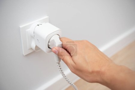 Foto de Uso de enchufe inteligente Wi-Fi en la pared en un hogar inteligente, controlando el consumo de electricidad - Imagen libre de derechos