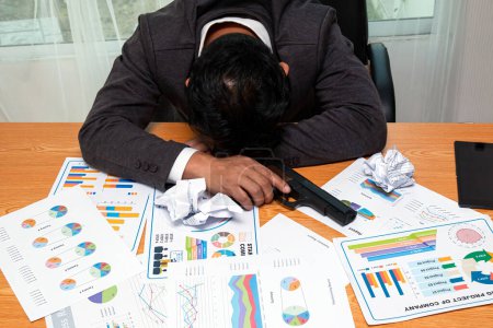 Photo for Criminal Tension in Business World: Stressed Asian Businessman sleep with holding Gun and many information graph sheet on desk in office - Royalty Free Image
