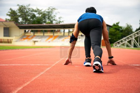 Téléchargez les photos : Asie adolescent mâle se préparer à courir sur la piste dans le stade, vue arrière angle bas - en image libre de droit