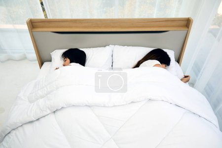 Une scène paisible de deux jeunes femmes dormant côte à côte, mettant en valeur la tranquillité et le confort d'une chambre moderne avec literie blanche