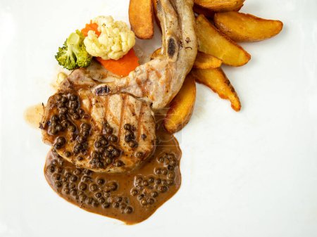 Grilled pork steak seasoned perfectly, topped with peppercorn sauce, served with roasted potatoes and mixed vegetables