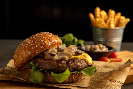 Close-up of mouthwatering cheeseburger topped with mushrooms and lettuce, paired with crispy fries and garnishes in the background