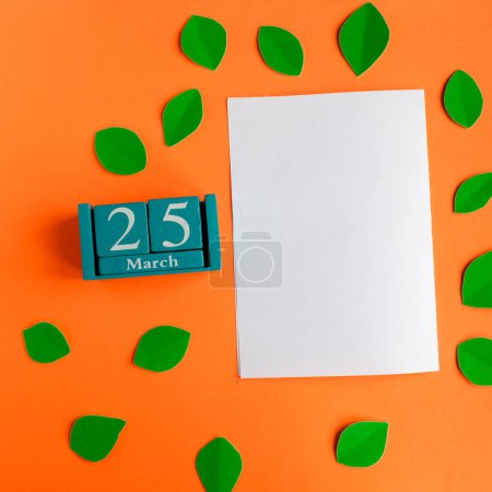 25 de marzo. Calendario de cubos azules y blanco maqueta en blanco sobre fondo naranja brillante
