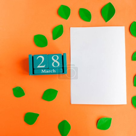 March 28. blue cube calendar and white mockup blank on bright orange background