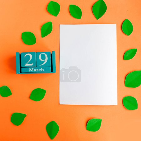 29. März blauer Würfel-Kalender und weiße Mockup-Rohlinge auf leuchtend orangefarbenem Hintergrund