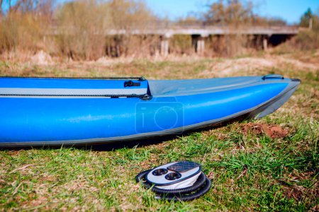 Blue rubber boat and pump on the grass