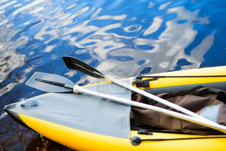 yellow inflatable boat with oars on the water
