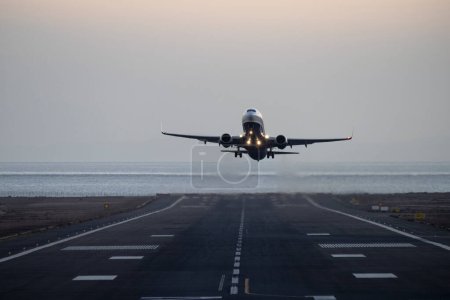 Foto de A frontal shot - an airplane takes off from an airport near the ocean shore in the evening - Imagen libre de derechos