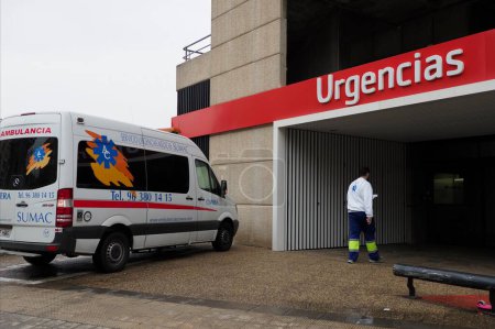 Foto de VALENCIA, ESPAÑA - 08 DE DICIEMBRE DE 2022: Ambulancia a la entrada del hospital, la enfermera entra en el hospital - Imagen libre de derechos