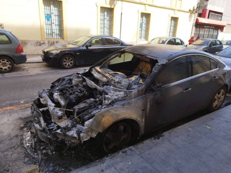 Foto de Un coche con una capucha quemada está estacionado en una calle de la ciudad - Imagen libre de derechos