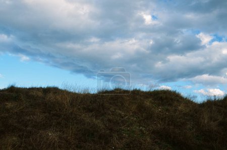 Foto de Pintoresca vista ángulo bajo de la colina áspera cubierta de hierba bajo el cielo nublado en el campo - Imagen libre de derechos