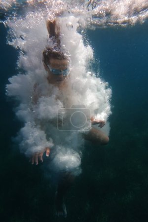 Foto de Vista submarina de un nadador con gafas en medio de una explosión de burbujas de aire - Imagen libre de derechos