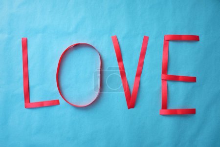 Téléchargez les photos : Le mot amour écrit avec un ruban cadeau sur fond bleu - en image libre de droit