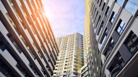 Photo for The narrow passage between modern residential buildings. Walls of high-rise apartment buildings and a narrow strip of sky between them. Modern urban living districts. Bottom view. - Royalty Free Image