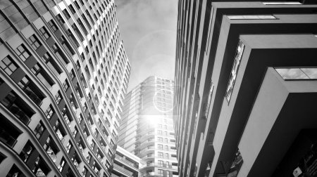 Photo for The narrow passage between modern residential buildings. Walls of high-rise apartment buildings and a narrow strip of sky between them. Modern urban living districts. Bottom view. Black and white. - Royalty Free Image