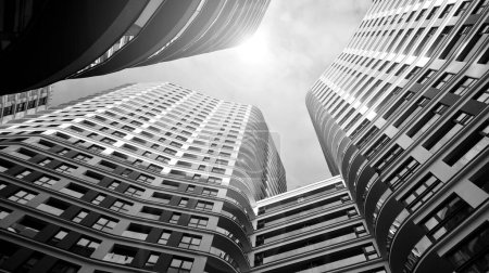 Photo for The narrow passage between modern residential buildings. Walls of high-rise apartment buildings and a narrow strip of sky between them. Modern urban living districts. Bottom view. Black and white. - Royalty Free Image
