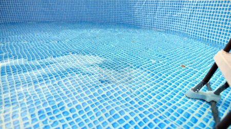 Water flowing from the hose into the pool filling. The inside of the swimming pool.