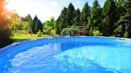 Piscina con marco de metal para el hogar y el jardín. Marco de la piscina en el patio. Jardín en el fondo. Vacaciones de verano diversión y recreación.