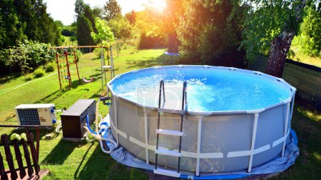Swimming pool with metal frame for home and garden. Frame swimming pool in the yard. Garden in the background. Summer holiday fun and recreation.