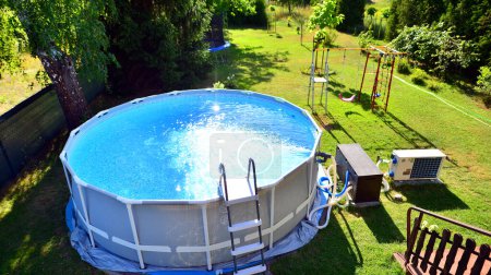 Swimming pool with metal frame for home and garden. Frame swimming pool in the yard. Garden in the background. Summer holiday fun and recreation.