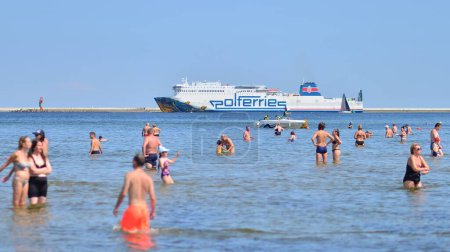 Téléchargez les photos : Swinoujscie, Pologne. 15 août 2023. Les gens se baignent sur la plage. En arrière-plan, le ferry Cracovie de l'opérateur de ferry Polferries sur son chemin de winoujcie en Pologne à Ystad en Suède - en image libre de droit