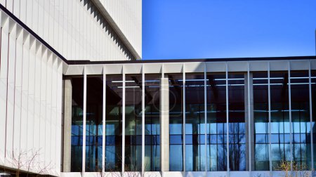 Modernes Bürogebäude in der Stadt mit Fenstern und einer Wand aus Stahl- und Aluminiumplatten. Zeitgenössische kommerzielle Architektur, vertikal konvergierende geometrische Linien.