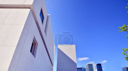 Foto de Luz del sol y sombra en la superficie de la pared del edificio de hormigón blanco contra el fondo azul del cielo, arquitectura exterior geométrica en estilo de fotografía de calle mínima - Imagen libre de derechos
