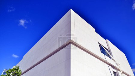 Sonnenlicht und Schatten auf der Oberfläche der weißen Betonmauer vor blauem Himmelhintergrund, Geometrische Außenarchitektur im Stil der Minimal Street Fotografie