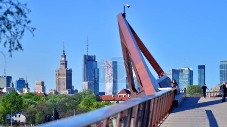 Warszawa, Polska. 11 kwietnia 2024 r. Most nad Wisłą przeznaczony tylko dla pieszych i rowerzystów. W tle panorama miasta z drapaczami chmur.