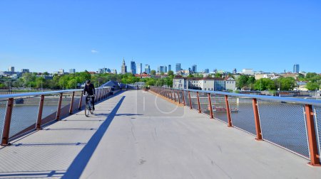 Warsaw, Poland. 11 April 2024. Bridge over the Vistula River intended only for pedestrians and cyclists. In the background, a panorama of the city with skyscrapers.