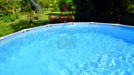 Schwimmbad mit Metallrahmen für Haus und Garten. Rahmenschwimmbecken im Hof. Garten im Hintergrund. Sommerferienspaß und Erholung.