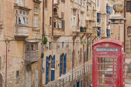Photo for Valetta, Malta - June 6, 2023: Red telephone box amongst historic buildings in the city of Valetta in Malta - Royalty Free Image