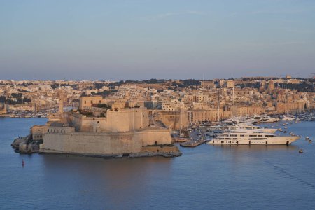 Photo for Valetta, Malta - June 7, 2023: View across the Grand Harbour at sunset from Upper Barrakka Gardens to Birgu and Senglea in Malta - Royalty Free Image