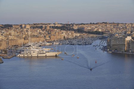 Photo for Valetta, Malta - June 7, 2023: View across the Grand Harbour at sunset from Upper Barrakka Gardens to Birgu and Senglea in Malta - Royalty Free Image