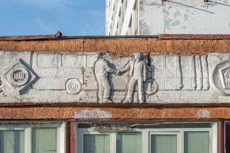 Photo for Old abandoned white bas-relief on the theme of transport on the facade of an old bus park with with a bus and workers shaking hands. Kyiv, Ukraine - March 2021. - Royalty Free Image