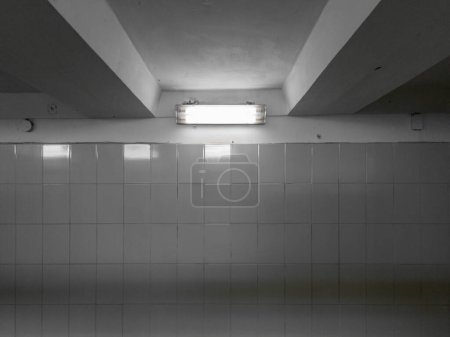 Foto de Una lámpara en un oscuro pasaje subterráneo, cuyas paredes están forradas con azulejos brillantes. - Imagen libre de derechos
