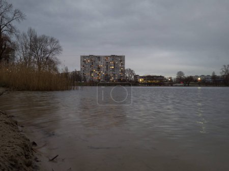 The lake in the evening with concrete multi storey skyscraper on the background.