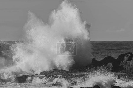 Schwarz-Weiß-Foto großer Wellen, die mit Wucht auf die vulkanischen Felsen an der Nordküste Teneriffas, Kanarische Inseln, treffen