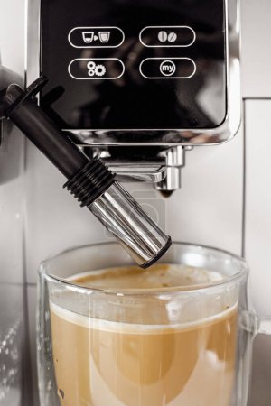Photo for Coffee drink with milk foam in a coffee machine. Home coffee machine. Coffee with milk. Glass cup. Morning coffee. Coffee break. Barista job. Tasty warming drink. - Royalty Free Image