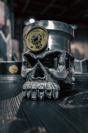 Photo for A metal ashtray in the form of a human skull on the bar counter. Iron skull. Human skeleton. Biker attributes. Metal products. Face without skin. - Royalty Free Image