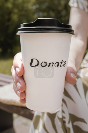 Téléchargez les photos : Tasse en papier avec café et l'inscription "faire un don". Café à emporter. Don en lieu et place du café. Partager avec les autres. Aider les gens. Aide mutuelle ukrainienne. Des gens gentils. La foi dans les gens. Appel pour faire un don. - en image libre de droit