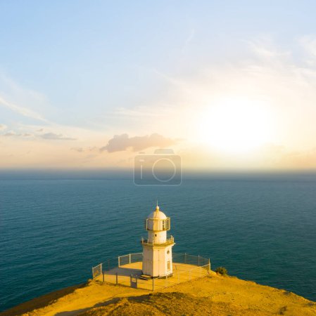 Foto de Faro blanco sobre capa marina al atardecer - Imagen libre de derechos