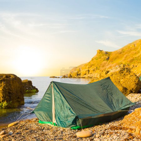 kleines touristisches Zelt an der Küste bei Sonnenaufgang, am frühen Morgen Meer Zeltplatz Szene